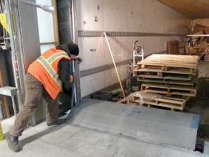 Photo by Jenny Neyman, Redoubt Reporter. James Epling, a warehouse worker at Lynden Transport’s new facility in Soldotna, sets dock plates into place on a trailer. The plates are outside the bay doors, so the doors can be closed to minimize heat loss. 