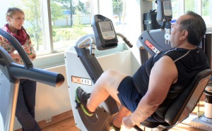 Exercise physiologist and tobacco program coordinator Amber Delago-Harrison advises Eric Morrison in the activity room as he pedals on a stationary bike.