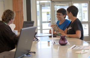 Karen Tollackson, left back, and Sharon Isaak, front right, chat at the center's reception desk as Isaak explains how she made a birch-bark basket she recently completed in a wellness activity arts and crafts class held at the center.